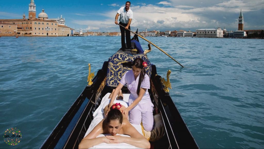 ماساژتراپیست در حال ماساژ گاندولا دادن زن جوان بر روی قایق ونیزی است.