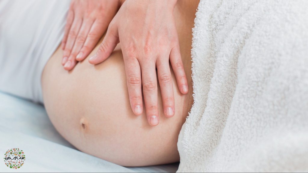 ماساژتراپیست شکم زن باردار را با دو دست خود ماساژ میدهد