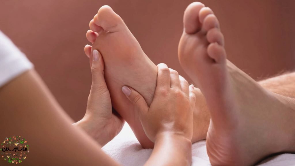 ماساژ رفلکسولوژی پای آقا توسط ماساژدرمانگر زن، من دراز کشیده و زن با دو دست خود در حال ماساژ دادن پای او است